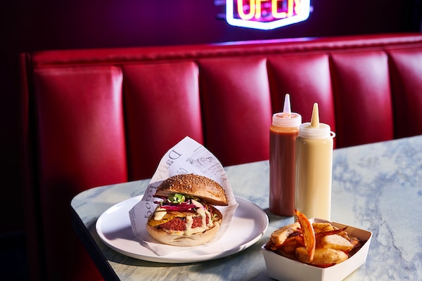Un hamburger emballé dans un papier et une barquette de frites